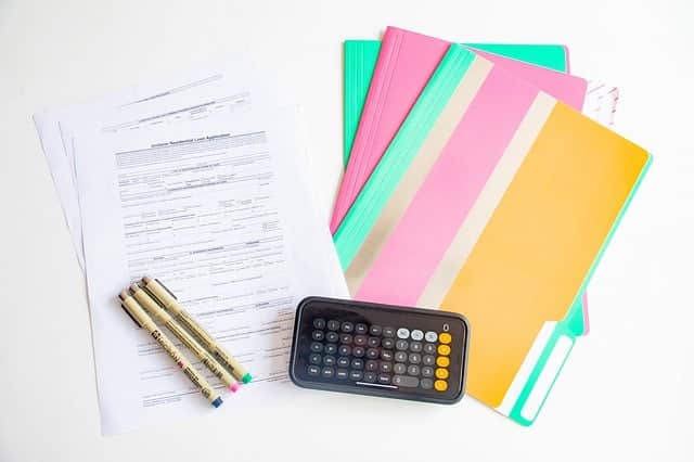 Calculator, folders, paper and pens on a work desk