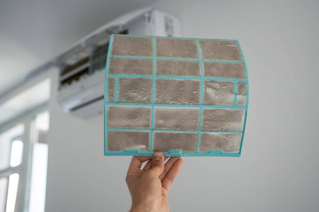 Person removing dirty filter as maintenance for the entire HVAC system, return ducts included